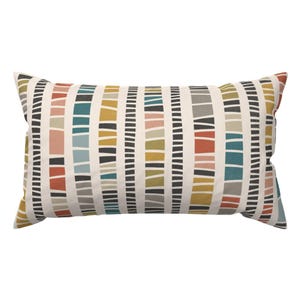 May include: A rectangular throw pillow featuring a cream-colored background with a repeating pattern of vertical stripes. The stripes are composed of stacked, irregular rectangular blocks in shades of mustard yellow, teal, terracotta, pink, and charcoal gray.