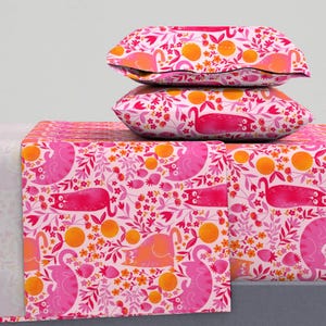Puede incluir: Juego de cama rosa y naranja con un patrón de gato y flores. El juego incluye una sábana plana, una sábana bajera y dos fundas de almohada.