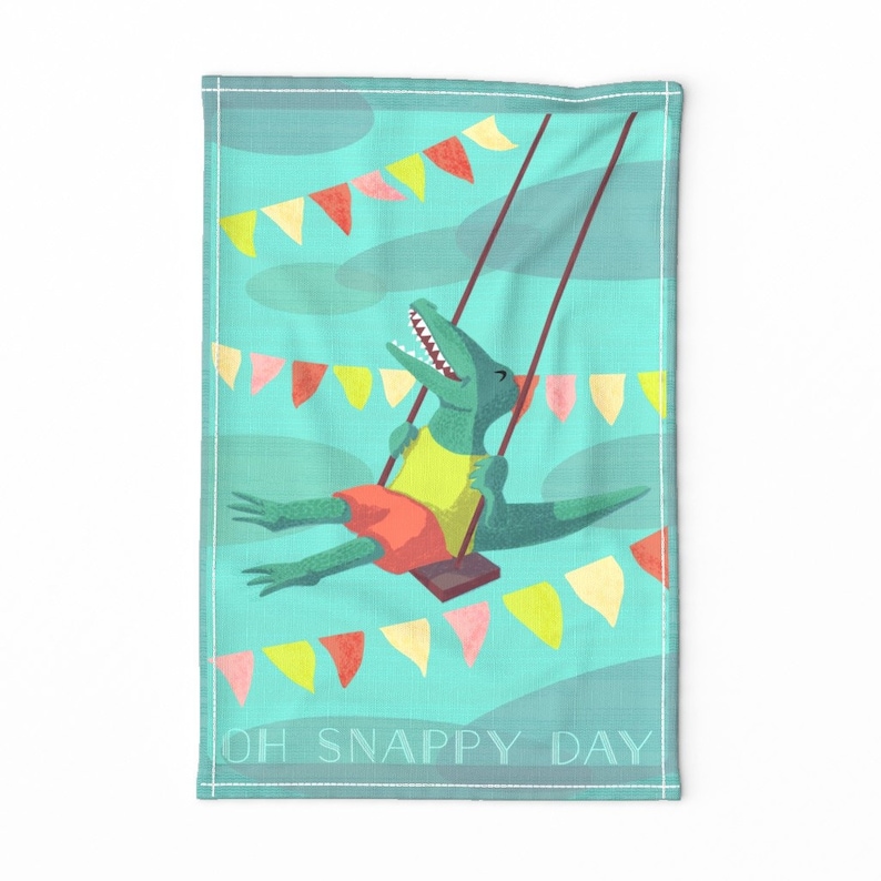 May include: A green alligator wearing a yellow shirt and red shorts is swinging on a swing set.  The background is a turquoise blue with yellow, pink, and orange pennant flags. The text "OH SNAPPY DAY" is at the bottom of the image.