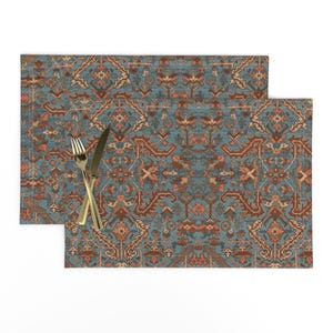 Può includere: Un set di due tovagliette all'americana blu e rosse con un design tradizionale. Le tovagliette sono realizzate in tessuto intrecciato e hanno un bordo a frangia.