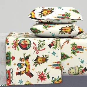 May include: A white Christmas themed bedding set featuring a variety of festive designs including snowmen, ornaments, candles, and a lantern. The bedding set has a white background with colourful accents.