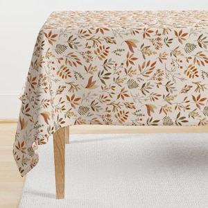 May include: A beige tablecloth with a repeating pattern of brown, orange, and green leaves and berries.