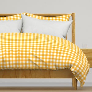 May include: A yellow and white gingham duvet cover on a wooden bed frame. The duvet cover is made of soft, comfortable fabric and has a classic checkered pattern.