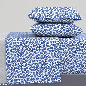 May include: A white and blue patterned bedding set with a blue and white patterned pillow. The bedding set has a blue and white leopard print.