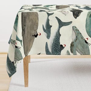 May include: A cream-colored tablecloth featuring a repeating pattern of various whales in shades of gray, blue, and green. Small figures wearing black suits and red hats are depicted climbing or interacting with the bodies of the large whales.