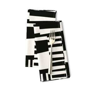 May include: Two cloth napkins folded together, featuring a black and white geometric pattern. A silver fork is placed on top.