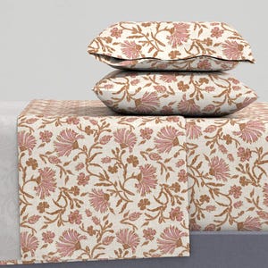 May include: A white bedding set with a floral pattern in shades of pink and brown. The set includes a flat sheet, fitted sheet, and two pillowcases.