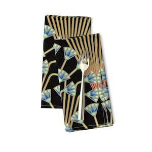 May include: A set of two black linen napkins with a geometric pattern of blue, green, gold, and red stylized lotus flowers. The napkins are folded and a silver fork is placed on top.