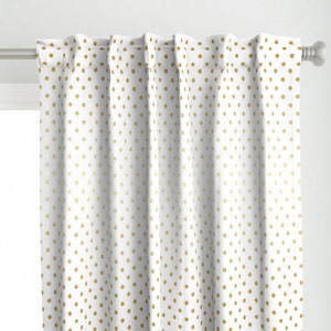 Könnte beinhalten: Weißer Vorhang mit einem sich wiederholenden Muster aus goldenen Polka-Dots. Der Vorhang hängt an einer silbernen Stange und bedeckt teilweise ein Fenster. Der Stoff hat ein weiches, strukturiertes Aussehen.