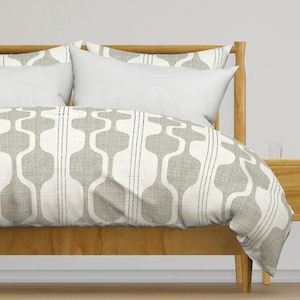 May include: A gray and white patterned duvet cover with a geometric design. The duvet cover is on a bed with a wooden headboard.