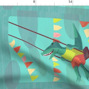 May include: A green alligator wearing a yellow shirt and red shorts is swinging on a swing set against a turquoise background with colorful flags.