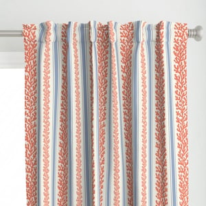 May include: Curtain panels with a coral and blue striped design. The curtains have vertical stripes of coral-coloured coral reef patterns and blue stripes against a cream background. They are hanging on a silver curtain rod.