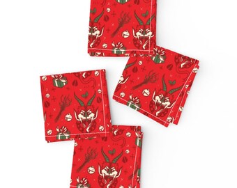 May include: Set of four red fabric napkins with a repeating pattern of a green and red Christmas devil head, a green holly sprig, a red bell, and a green and red gift box.