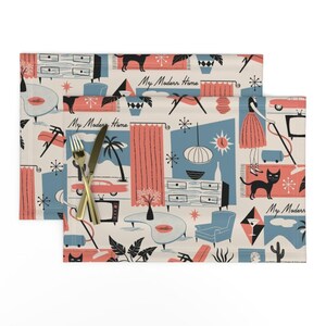 May include: Two rectangular placemats with a mid-century modern design. The cream-colored background features illustrations of furniture, cars, cats, and plants in coral, black, and blue. The text "My Modern Home" is also visible.