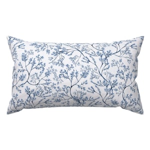 May include: A white rectangular pillow with a blue floral pattern. The pattern features delicate branches with small blue flowers.