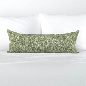May include: A long, rectangular lumbar pillow featuring an olive green fabric base with a repeating pattern of small, vertical, off-white dash marks distributed evenly across the entire surface of the pillow cover.