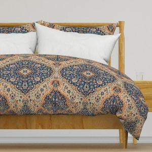 Könnte beinhalten: Ein Bettbezug mit einem Muster in Marineblau und Orange. Der Bettbezug liegt auf einem Holzbettgestell mit einem weißen Kissen darauf.