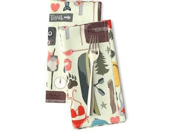 May include: Two green and white fabric napkins with a repeating pattern of camping and outdoor adventure themed illustrations. The illustrations include a compass, a tent, a canoe, a bear paw print, a swimsuit, a first aid kit, a fishing rod, a campfire, and a trail sign that says "Trail".