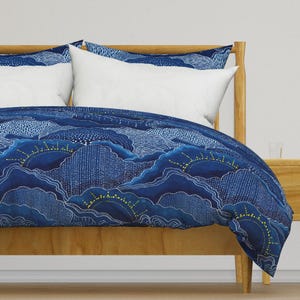 May include: A blue and white duvet cover with a pattern of clouds and suns. The duvet cover is made of a soft, comfortable fabric and features a subtle shimmer.