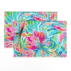 May include: Two colorful placemats with a swirling abstract floral pattern in shades of pink, orange, blue, green, and white.