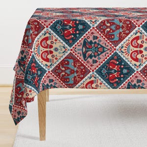 May include: A red, blue, and cream tablecloth with a Scandinavian-inspired Christmas pattern. The pattern features stylized reindeer, birds, and Christmas trees.
