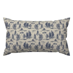 May include: A beige throw pillow with a blue and white pattern of trees, tents, and flying saucers. The pattern is repeated throughout the pillow.