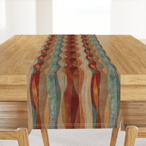 May include: A brown, orange and teal table runner with a wavy abstract pattern. The runner is on a wooden table.