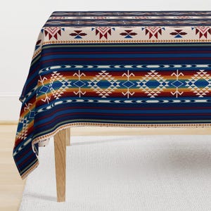 May include: A rectangular tablecloth with a Southwestern-inspired design. The tablecloth features a repeating pattern of geometric shapes in shades of blue, red, yellow, and cream. The design is set against a dark blue striped background.