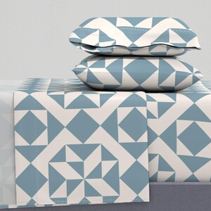 May include: A white and blue geometric patterned bedding set with two matching pillowcases. The bedding features a repeating pattern of squares and triangles.