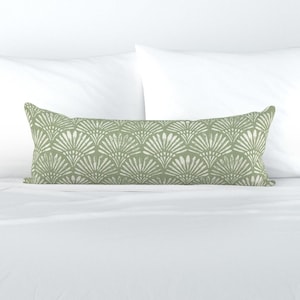 May include: A sage green lumbar pillow with a white geometric pattern. The pattern resembles a series of overlapping fans.