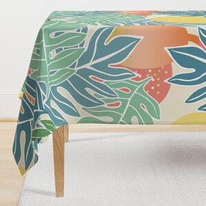 May include: A white tablecloth with a tropical leaf pattern in shades of green, blue, yellow, and orange. The leaves are stylized and abstract.