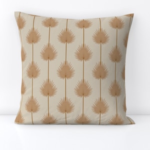Pode incluir: Uma almofada bege com um padrão repetido de folhas de palmeira marrons.