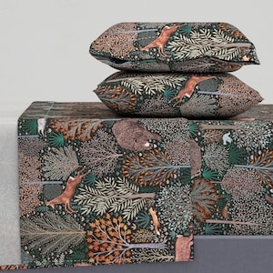May include: A dark green, brown, and orange patterned fitted sheet with a woodland scene featuring deer, bears, and birds. The sheet is folded and stacked on top of two matching pillowcases.