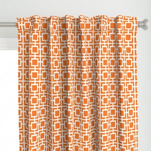 May include: Orange and white geometric patterned curtain panels. The pattern is a repeating square design.