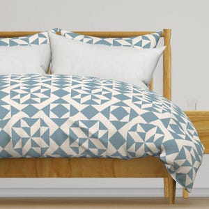 May include: A blue and white geometric patterned duvet cover on a wooden bed frame.
