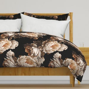 May include: A black duvet cover with a floral pattern featuring large, beige peonies on a black background. The duvet cover is shown on a bed with a white pillow and a wooden headboard.
