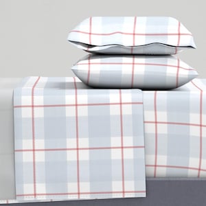 May include: A bedding set featuring a light blue and white plaid pattern with red accent lines. The set includes two pillows stacked on top of a flat sheet and a fitted sheet. The sheets and pillowcases have a classic, clean design.