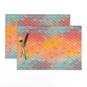 May include: A set of two placemats with a geometric pattern in shades of blue, green, orange, yellow, and red. The pattern resembles a sunset.