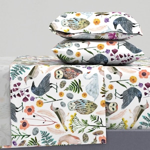 May include: White bedding with a repeating pattern of owls, birds, ferns, flowers, and feathers. The bedding is made of soft, comfortable fabric and is perfect for adding a touch of nature to your bedroom.