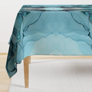 May include: A blue and white tablecloth with a marbled pattern. The tablecloth is draped over a table with wooden legs.