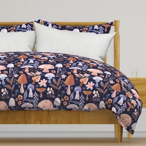 May include: A navy blue duvet cover with a whimsical mushroom and floral pattern. The duvet cover features a variety of mushrooms in shades of pink, orange, and brown, as well as delicate floral details. The background is a dark navy blue.