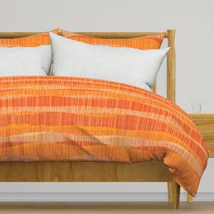 May include: Orange and yellow striped duvet cover on a wooden bed frame. The duvet cover has a subtle textured pattern.