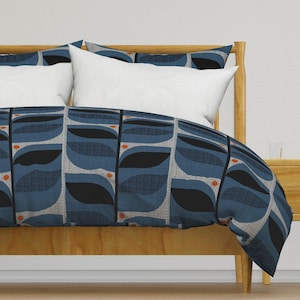 May include: A blue and black patterned duvet cover with orange accents. The duvet cover is on a wooden bed frame with white pillows.