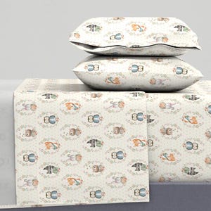 Op de afbeelding: Een wit beddengoedset met een bosdierprint met uilen, vossen, wasberen en konijnen. De beddengoedset bevat een hoeslaken, een plat laken en twee kussenslopen.