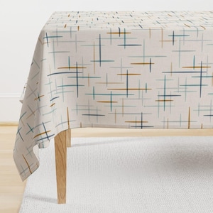 May include: A white tablecloth with a geometric pattern of blue, brown, and beige lines. The tablecloth is draped over a wooden table.