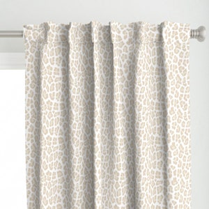 May include: Beige curtains with a white leopard print pattern.