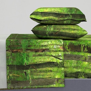 Könnte beinhalten: Bettwäsche-Set mit grünem und braunem Muster und zwei passenden Kissenbezügen. Das Muster zeigt eine Waldszene mit Bäumen und Blättern.