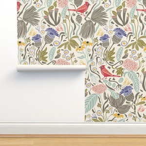 Può includere: Una carta da parati color crema con un motivo ripetitivo di cardinali rossi, cardi blu, foglie verdi e fiori gialli. La carta da parati è arrotolata e parzialmente srotolata, mostrando il motivo.