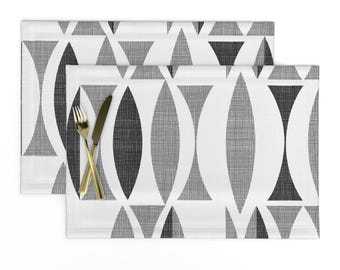 Könnte beinhalten: Ein Set mit zwei Platzsets mit geometrischem Muster in Schwarz und Weiß. Die Platzsets zeigen ein sich wiederholendes Muster aus überlappenden Kreisen und Dreiecken.