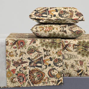 Könnte beinhalten: Ein Set aus drei cremefarbenen Kissenbezügen mit einem Vintage-Tattoo-inspirierten Design. Das Design zeigt eine Vielzahl von Bildern, darunter einen Schädel, einen Tiger, einen Pfau, ein Schiff, eine Rose und ein Herz.